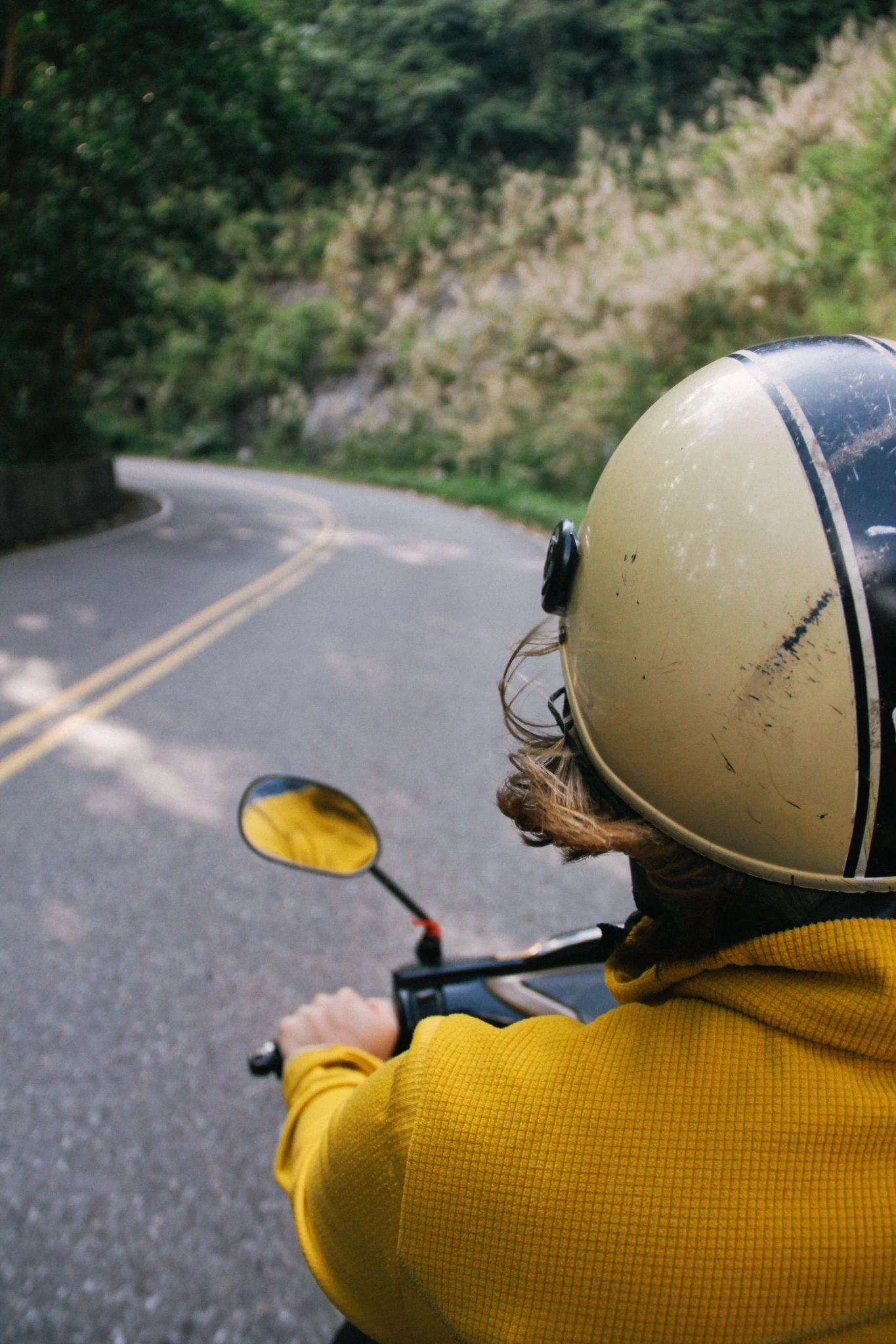 Entregador de moto, de capacete amarelo, numa estrada
